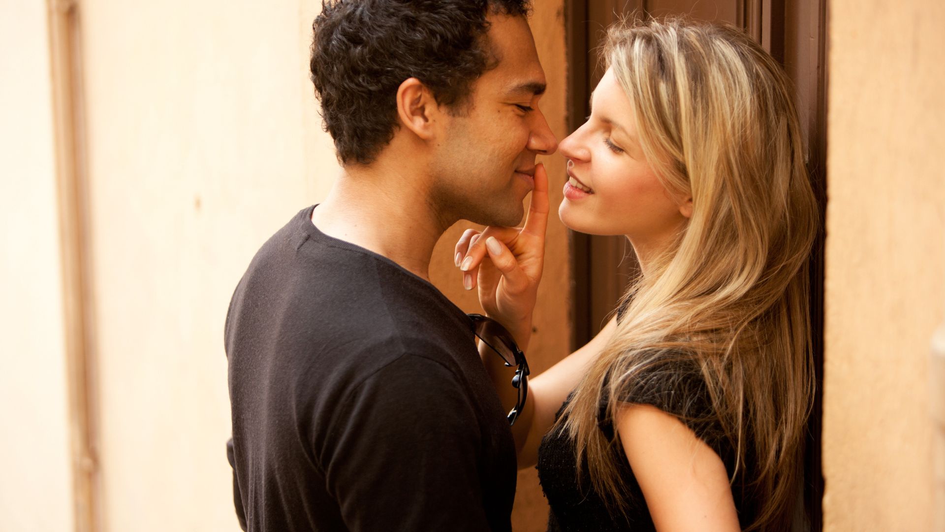Leaf de Getty Images para o Canva Pro Imagem de um casal, homem e mulher se acariciando. Ambos usam camiseta preta.