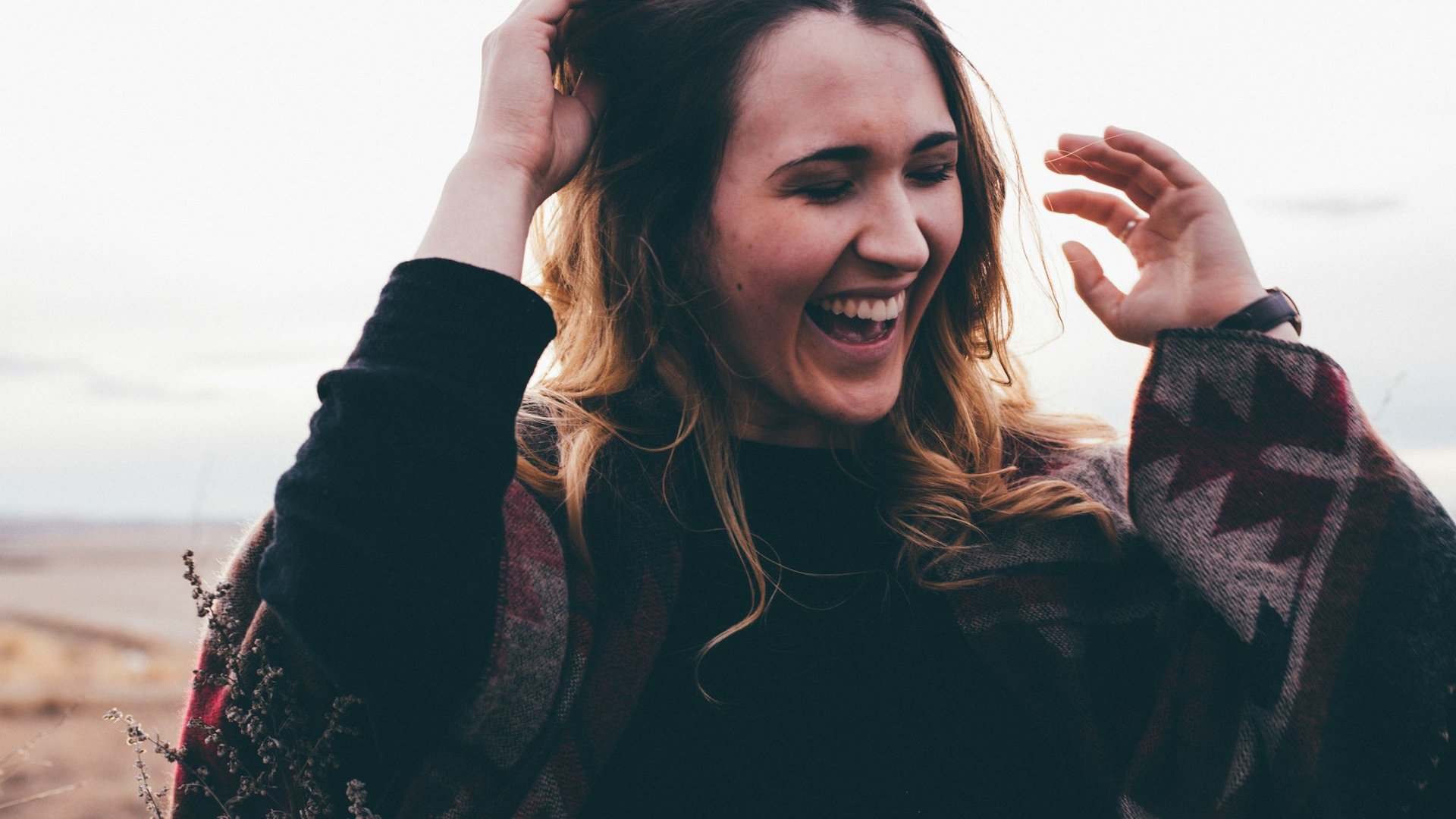 Priscilla Du Preez 🇨🇦 / Unsplash Mulher sorridente, agasalhada e ao ar livre.
