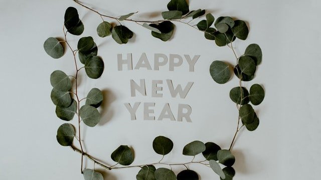 Unsplash / Kelly Sikkema Feliz Ano Novo e ramo de folhas ao redor