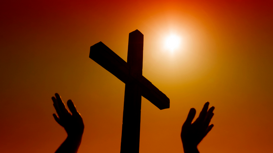 whitemay de Getty Images Signature / Canva Silhueta de cruz e mãos voltadas ao céu