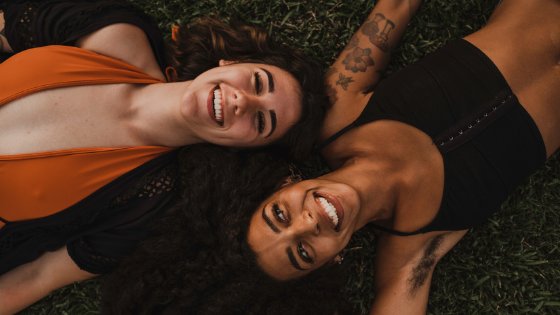Duas mulheres sorrindo deitadas em um gramado