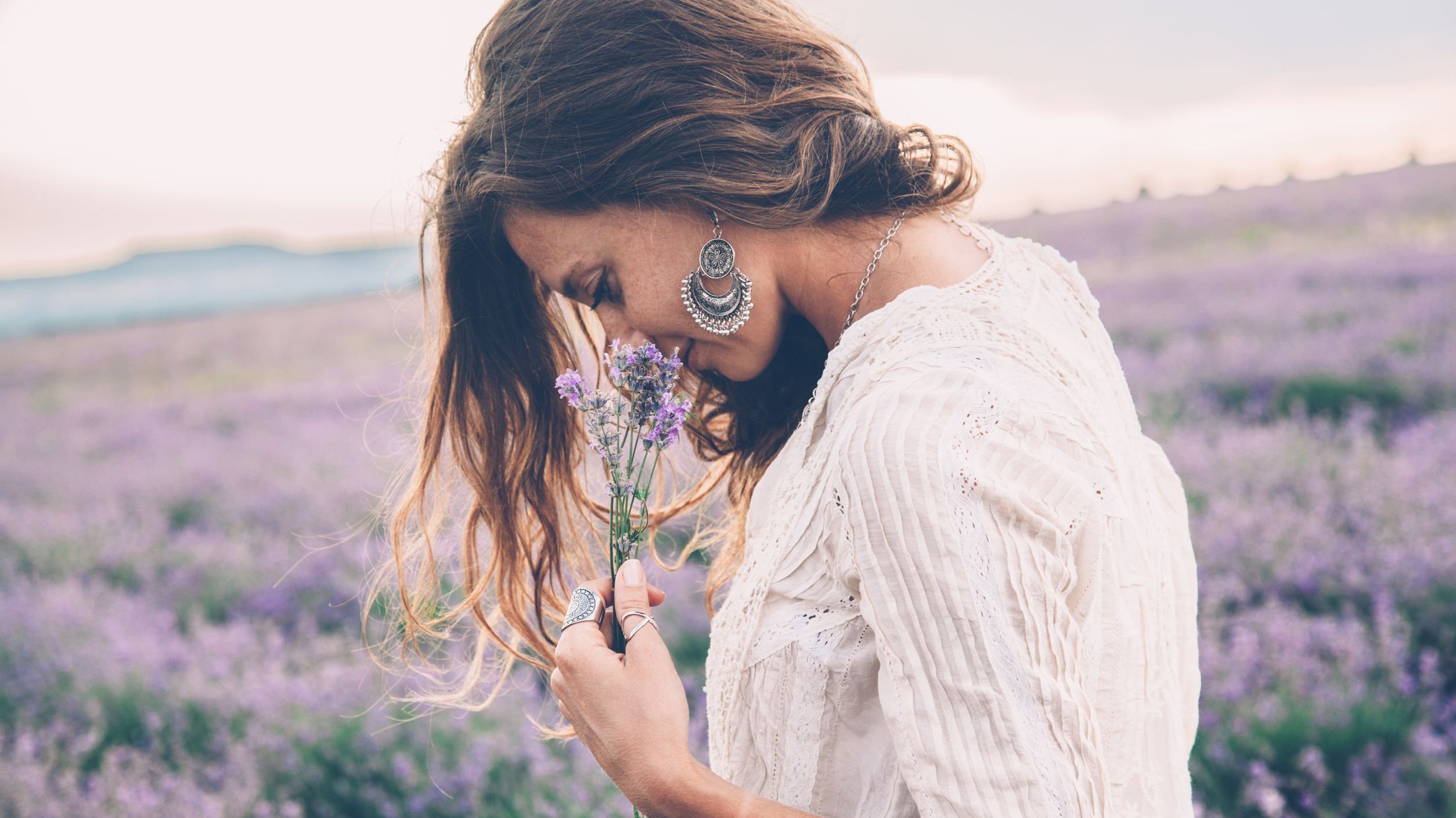 123RF Mulher em um campo de flores, segurando uma flor e a cheirando