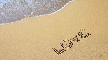 Palavra 'love' escrita na areia da praia