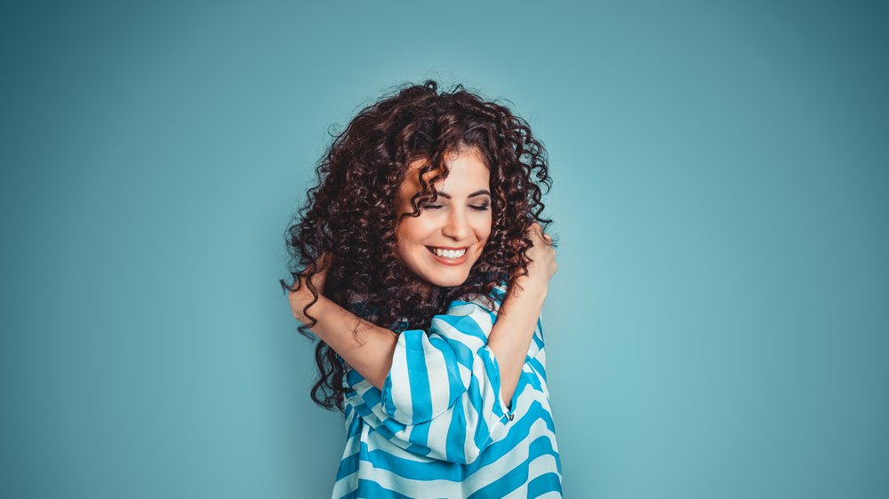 HBRH / Shutterstock.com Mulher se abraçando, em sinal de amor próprio