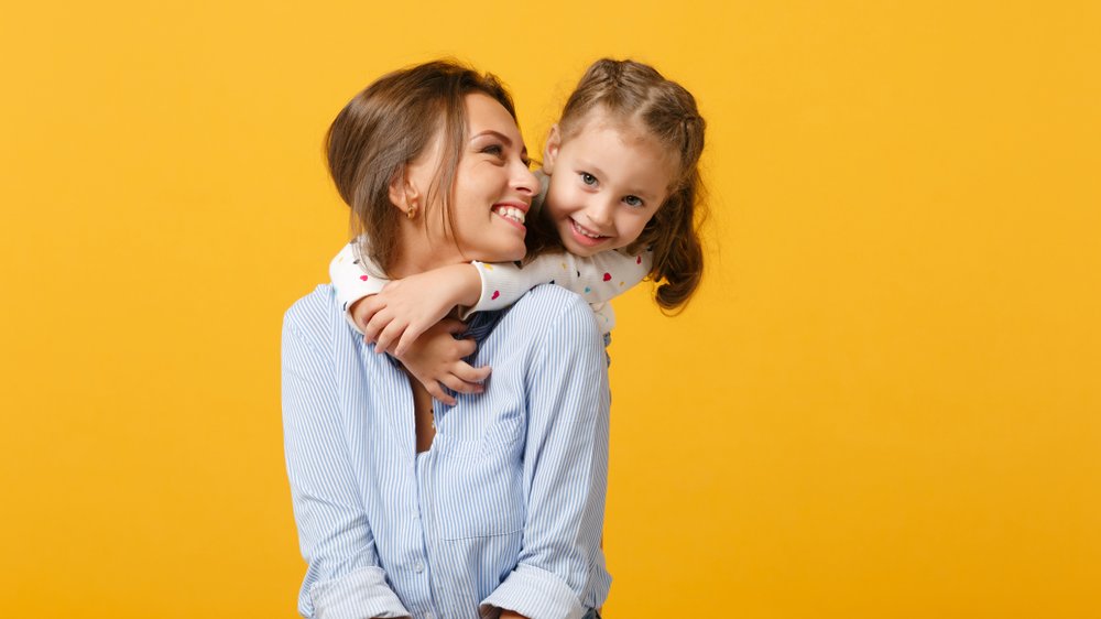 Menina sorrindo e abraçando mãe sorridente