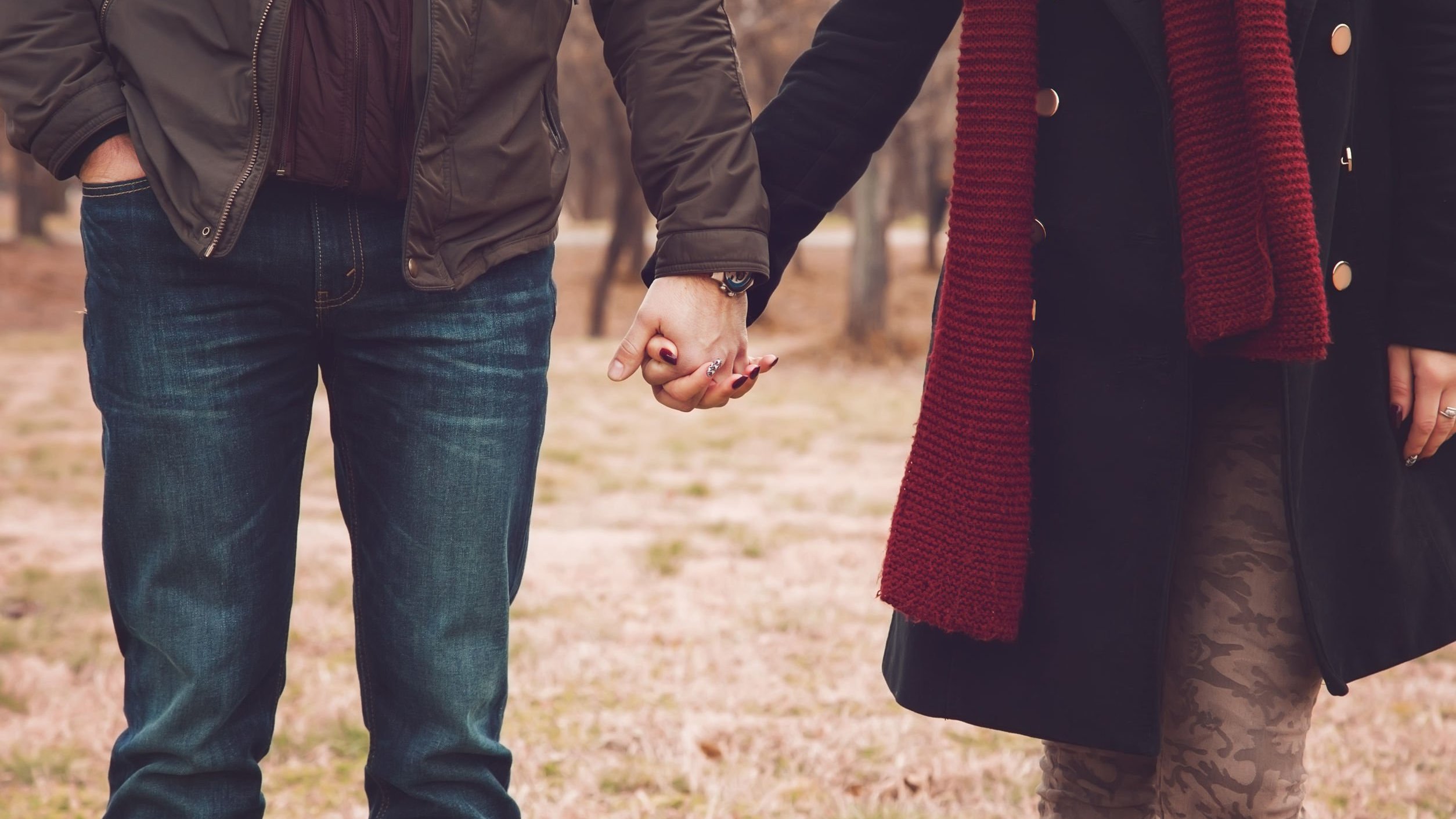 Homem e mulher usando roupas de frio, de mãos dadas, caminhando