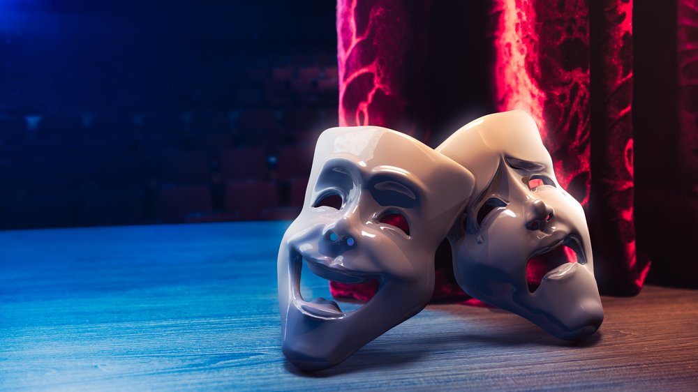Máscaras do teatro (comédia e drama) em cima de um palco de madeira