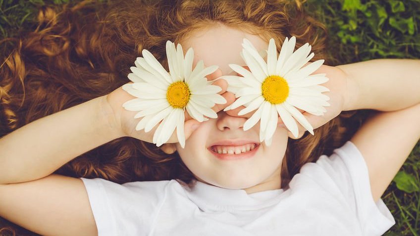Menina criança com flores nos olhos sorrindo