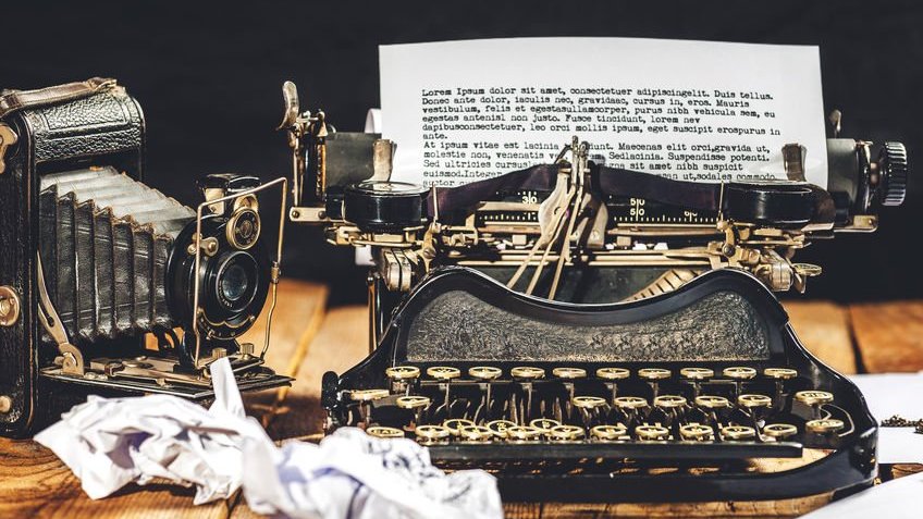 Máquina de escrever e câmera antiga com papel e rascunhos amassados