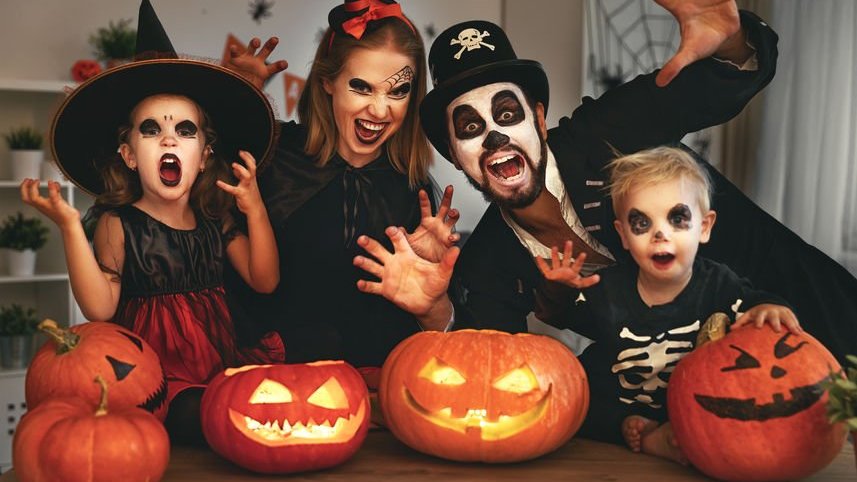 Família com fantasias de Halloween e abóboras decoradas na mesa