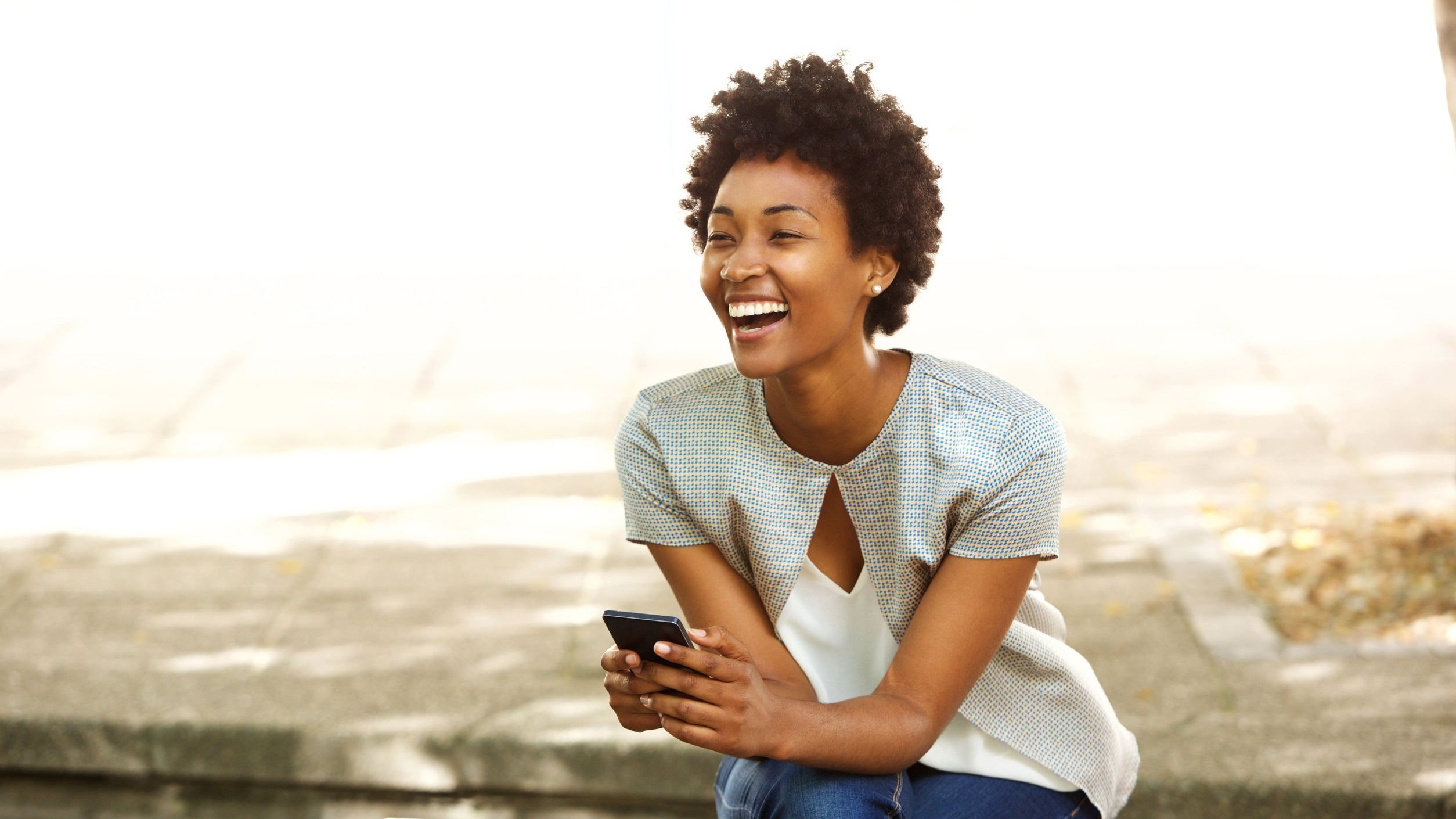 Mulher sorrindo enquanto segura um celular