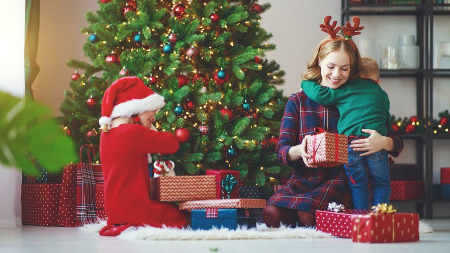 Mãe e filhos se abraçam ao lado da árvore de Natal