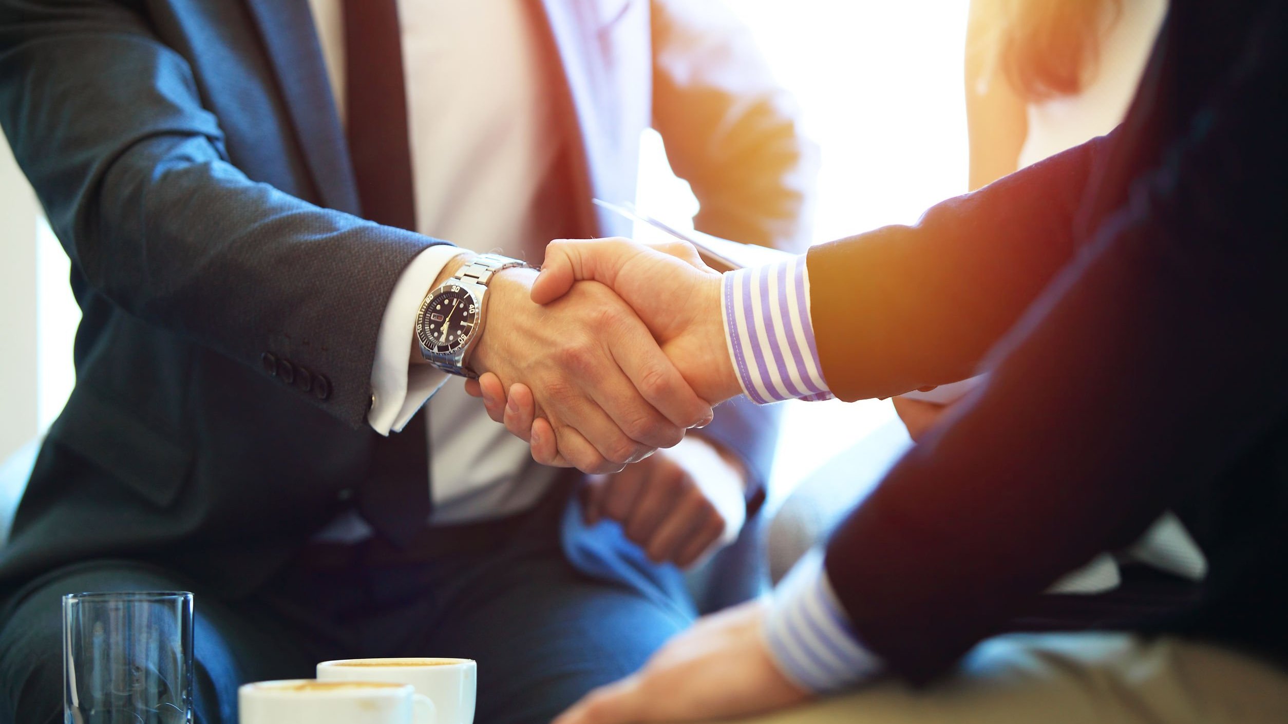 Duas pessoas em ambiente de trabalho apertam as mãos.