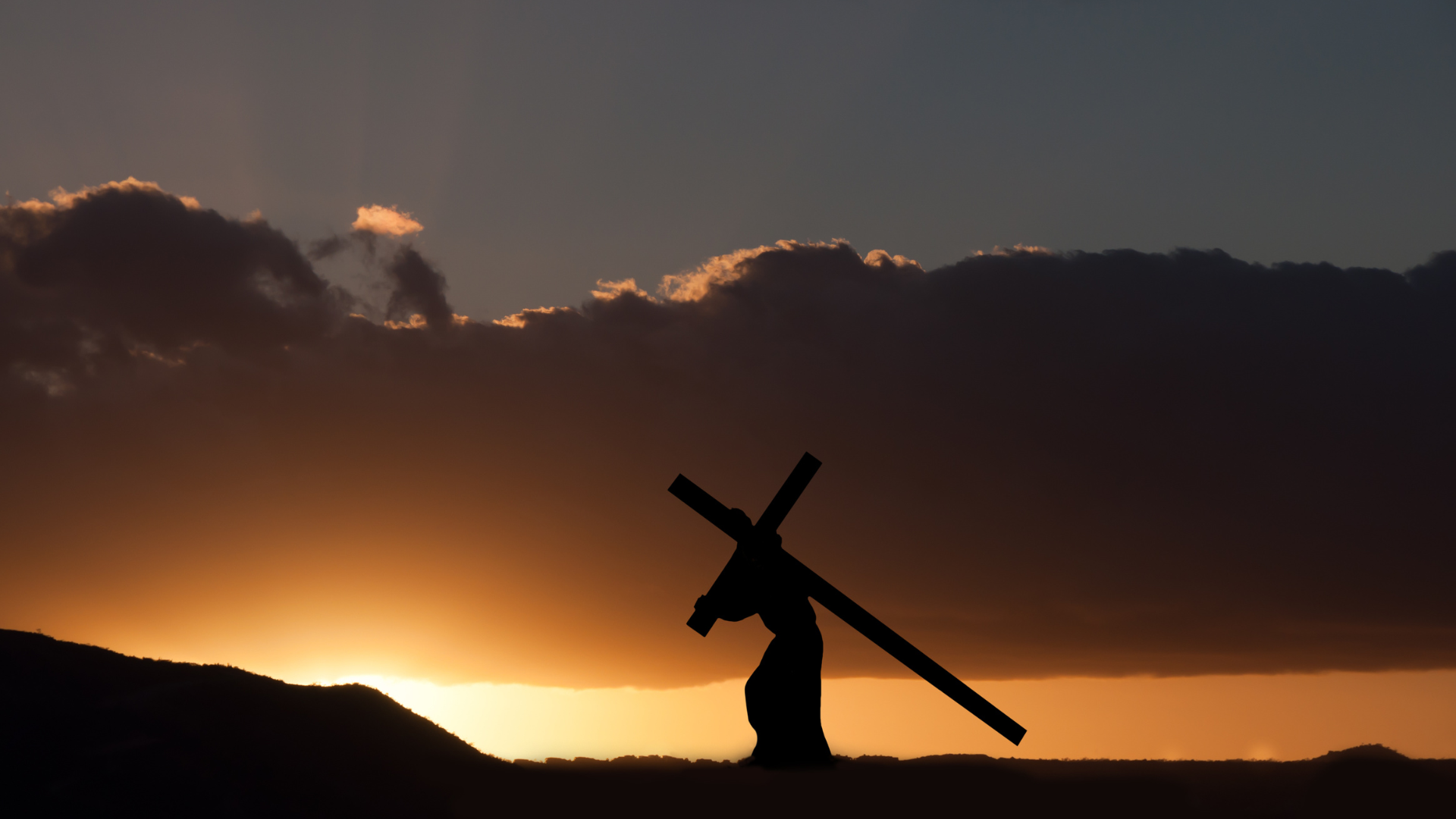 Paisagem alaranjada de fundo e Jesus carregando a cruz ao longe.