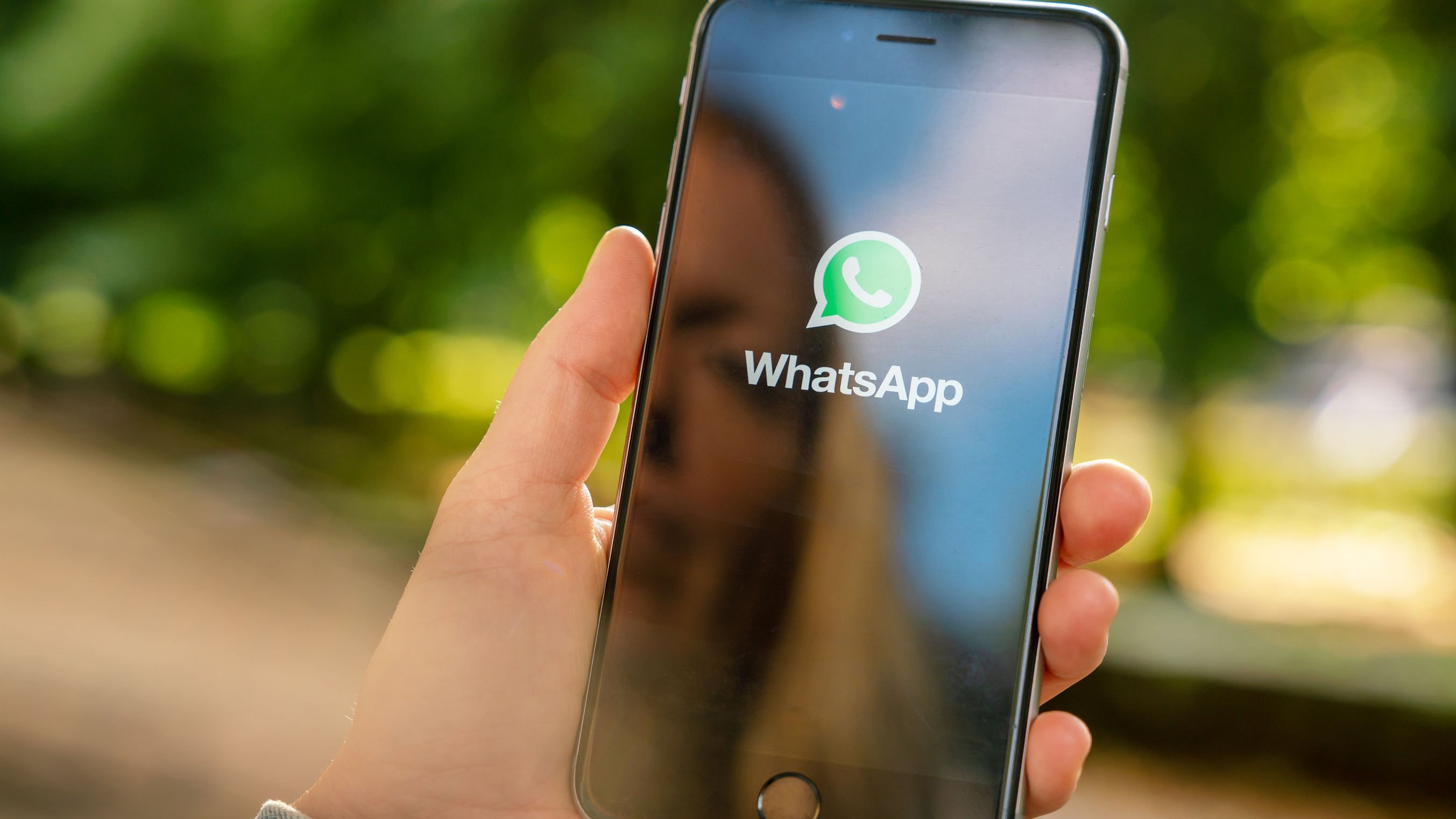 Mulher segurando celular abrindo aplicativo do WhatsApp