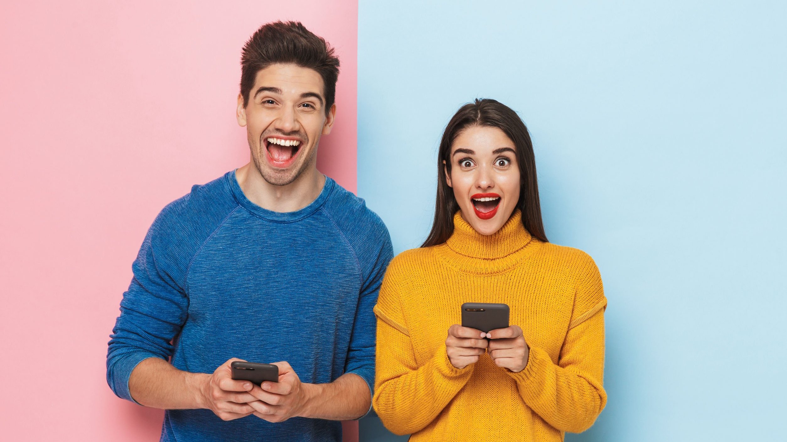 Homem e mulher segurando smartphones enquanto sorriem, lado a lado.