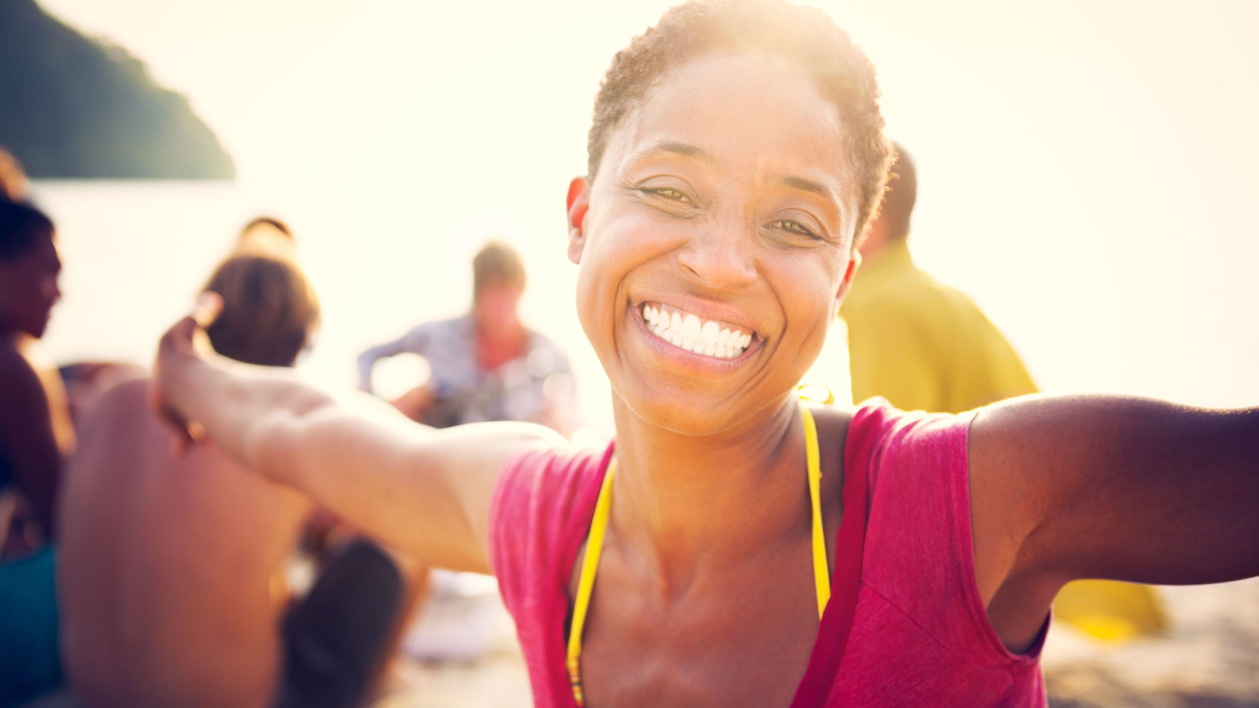 Mulher sorrindo com os braços abertos na praia