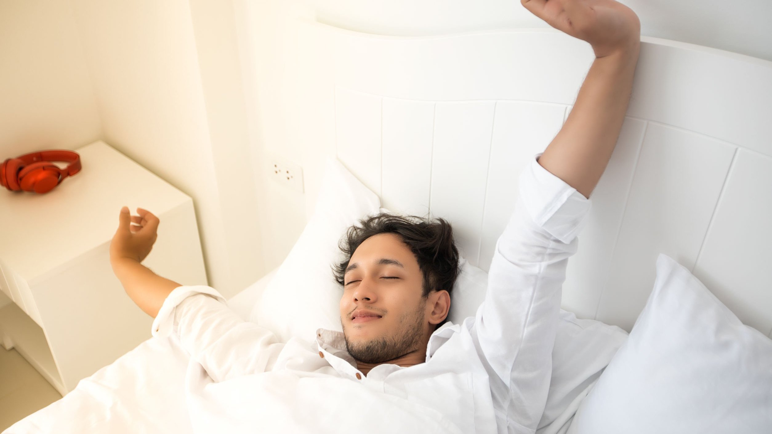 Homem se espreguiçando em sua cama durante a manhã