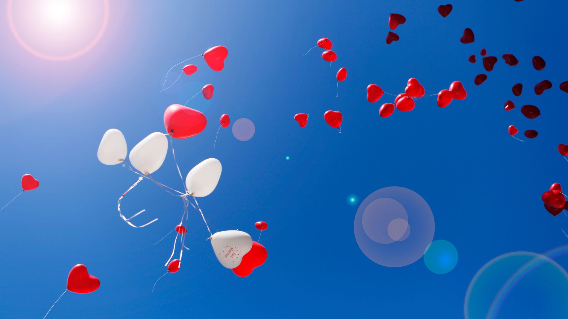 Imagem de balões de coração soltos pelo céu azul