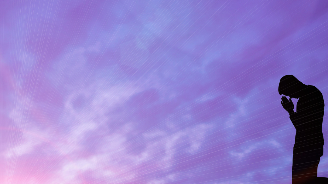 Foto de um homem ajoelhado com a paisagem do céu arroxeado ao seu redor.