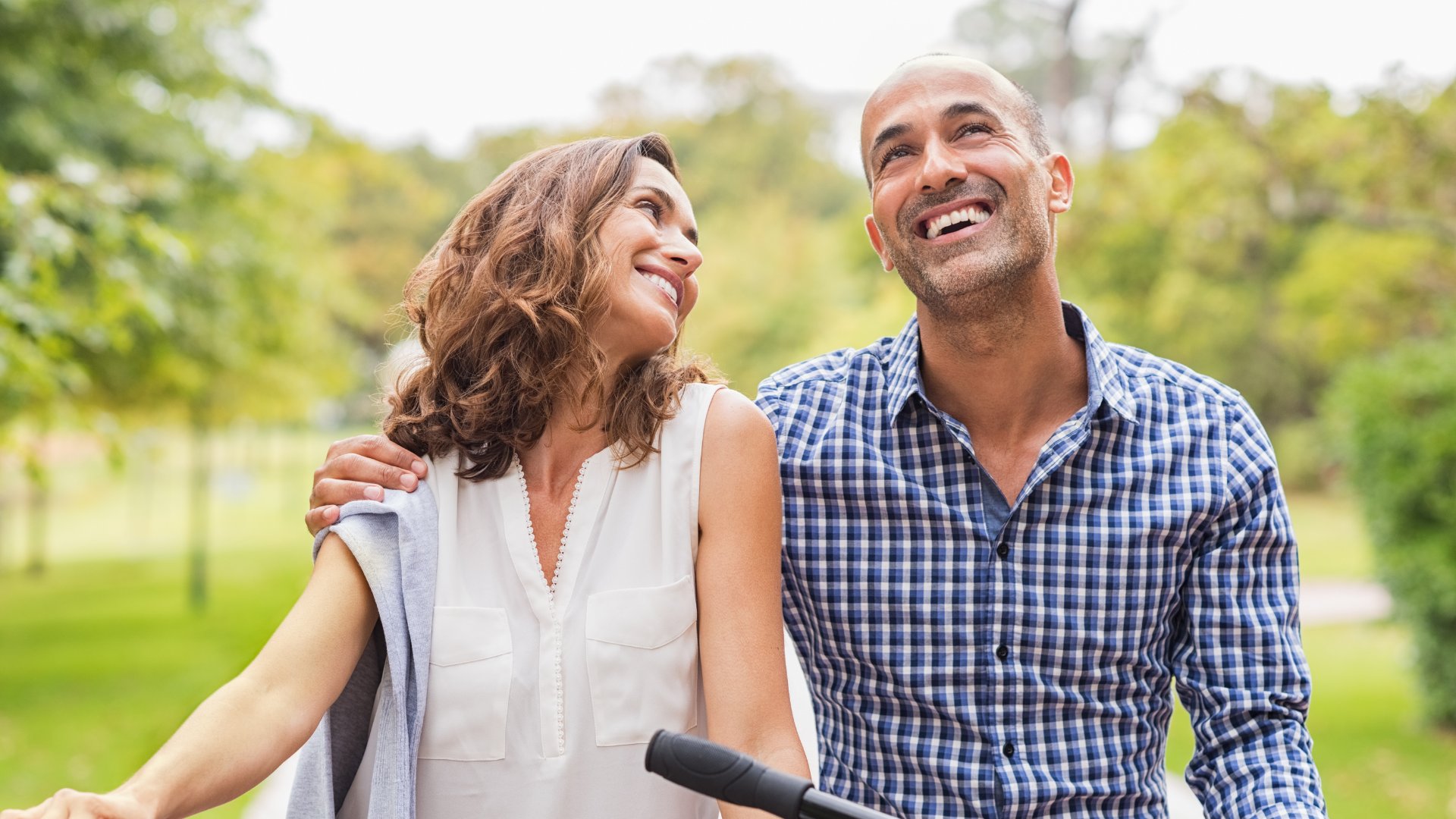 Ridofranz / Getty Images Pro / Canva Casal feliz andando de bicicleta no parque