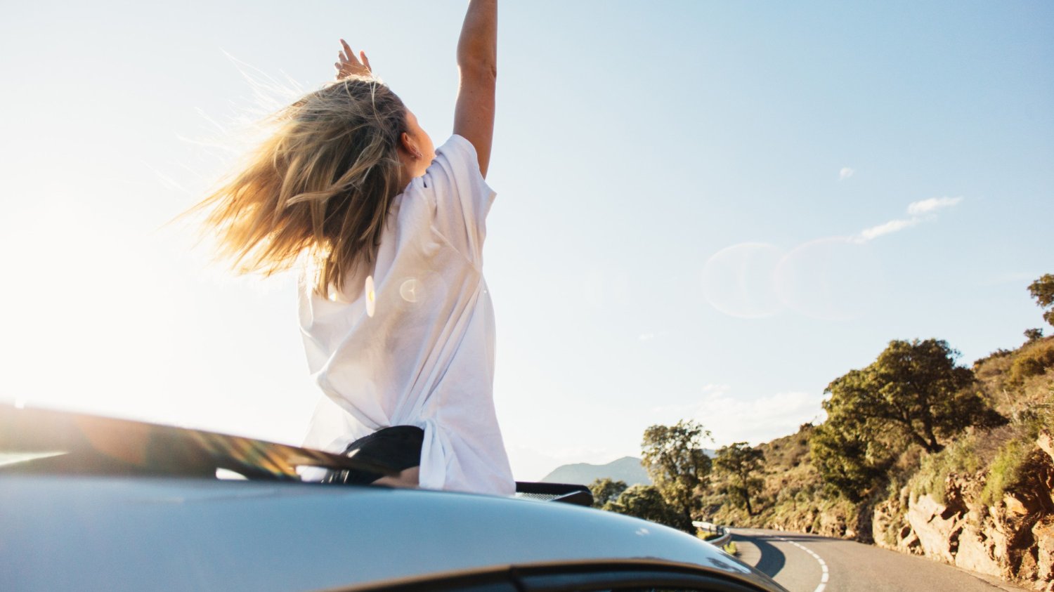 Mulher no teto solar de um carro no meio da estrada