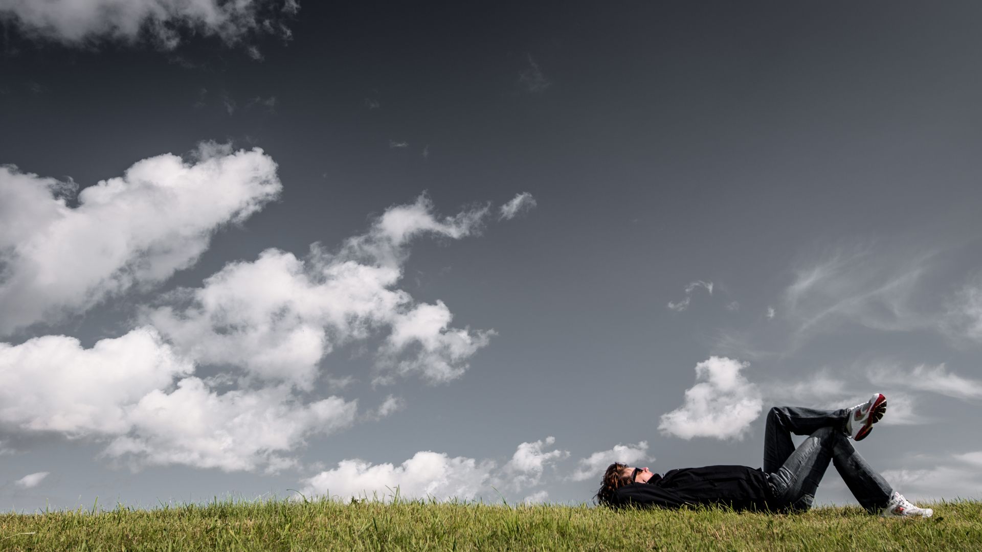 Imagem de um homem deitado em um campo e olhando para o céu.