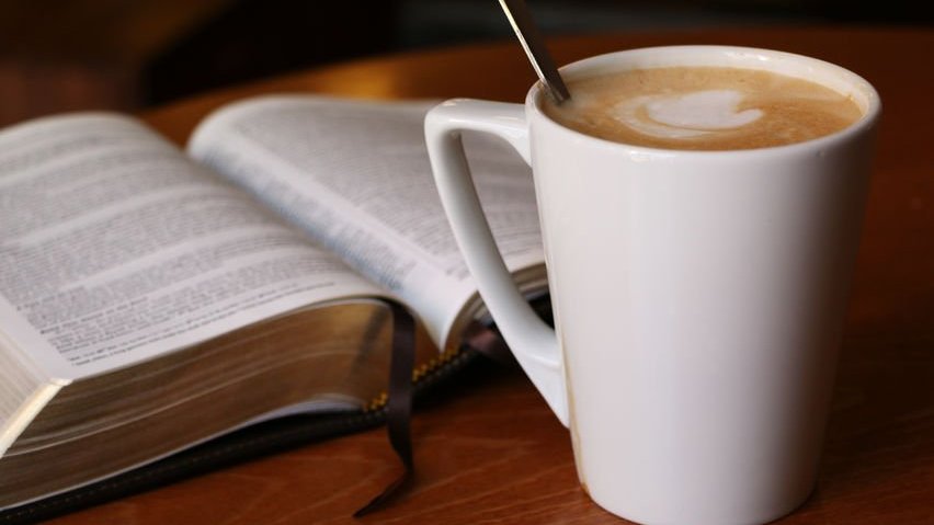 Foto de bíblia aberta com caneca de leite ao lado