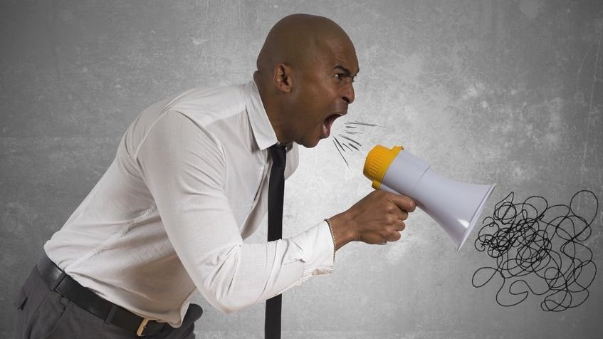 Homem em pé segurando megafone gritando