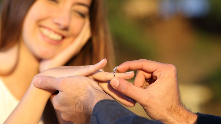 Homem colocando anel em mão de mulher