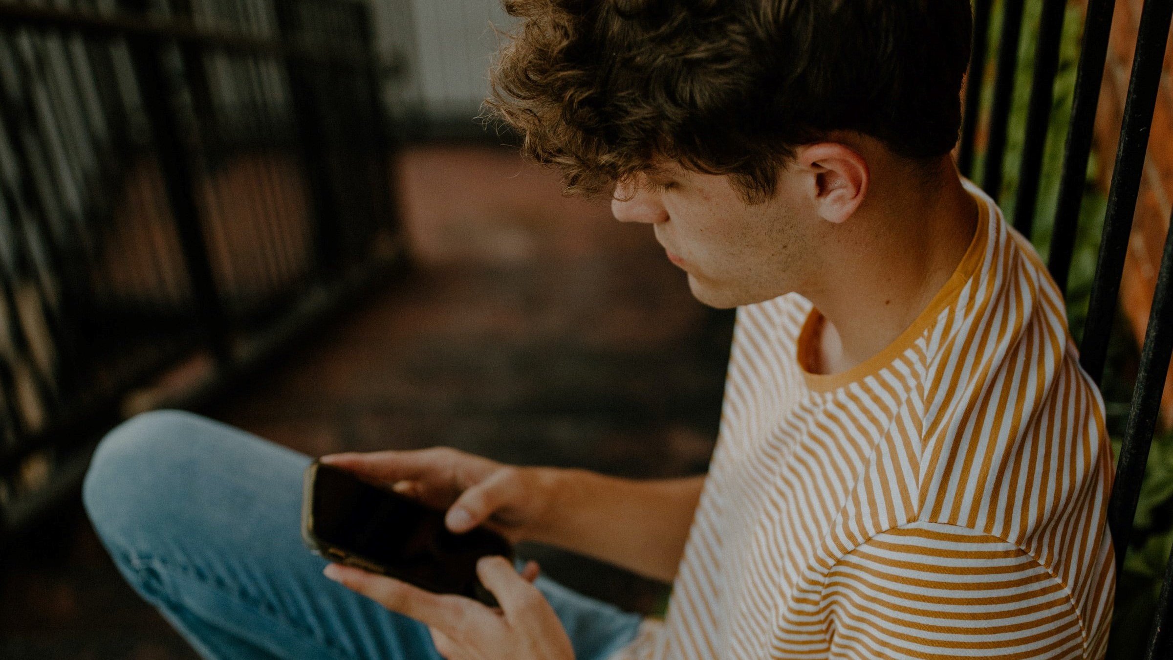 homem sentado na escada e mexendo no celular