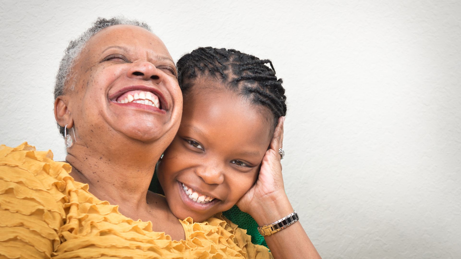 Imagem de uma senhora negra abraçando um garoto que parece ser seu neto, ambos estão sorrindo