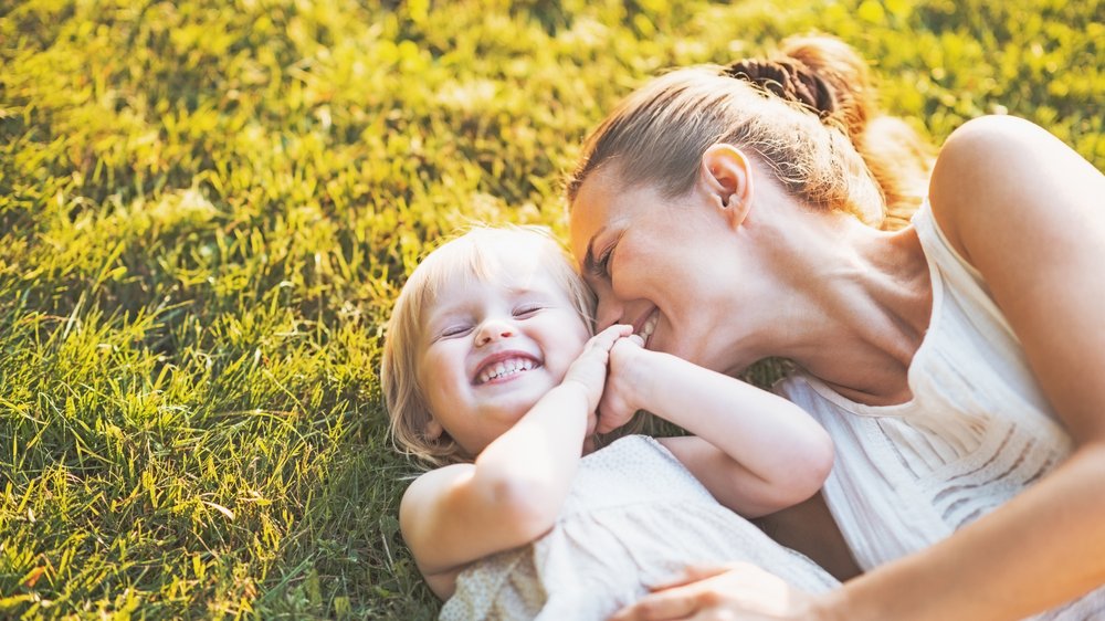 Mãe brincando com filha pequena no gramado