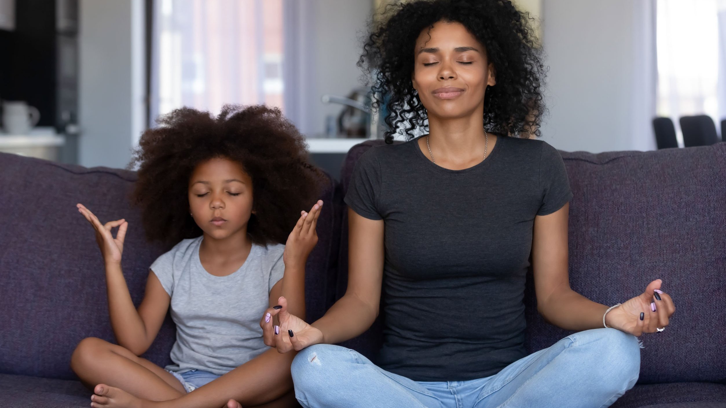 Mãe e filha meditando no sofá