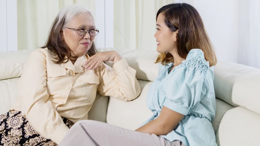 Duas mulheres sentadas no sofá enquanto conversam