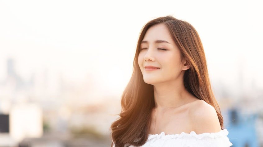 Mulher sorrindo de olhos fechados