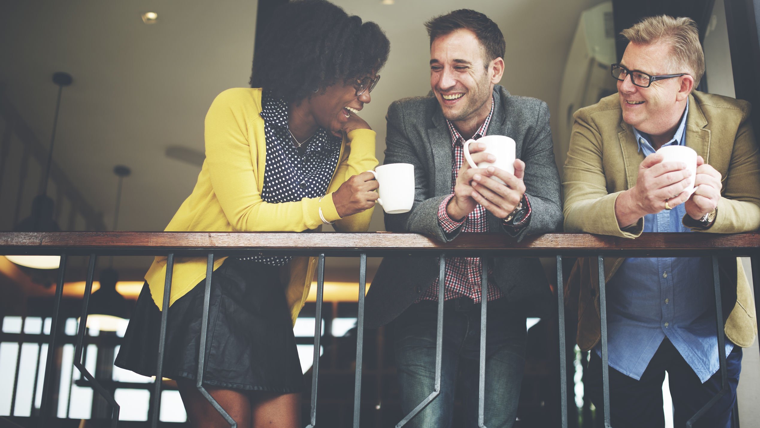 Colegas de trabalho rindo e tomando café