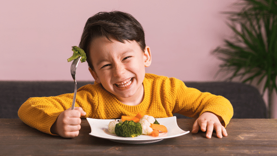 Criança comendo vegetais e sorrindo
