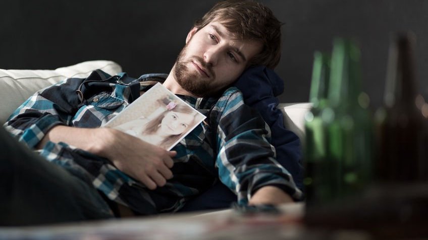 Homem deitado com foto de ex-namorada