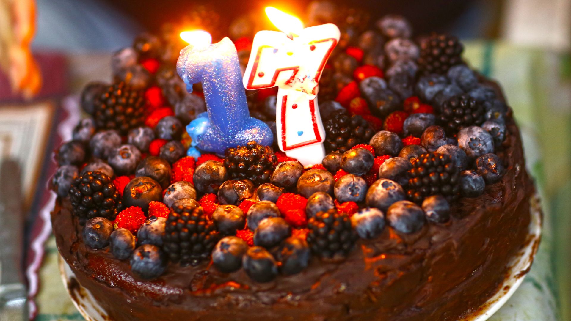 Imagem de um bolo de frutas vermelhas e uma vela de 17 de anos no topo
