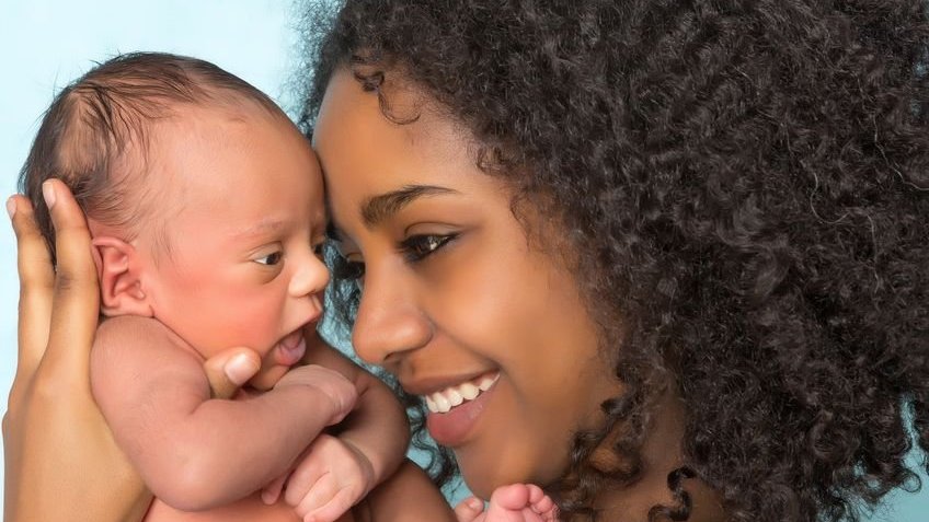 Mulher sorridente segurando um bebê recém-nascido.