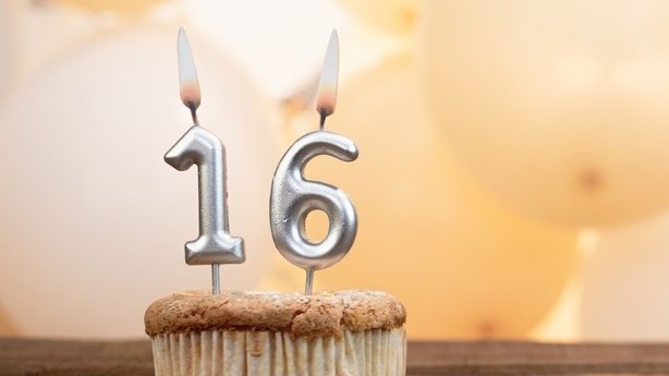 Andrii_Video Production / Shutterstock Velas com número 1 e 6 dispostas em um cupcake, com balões ao fundo.