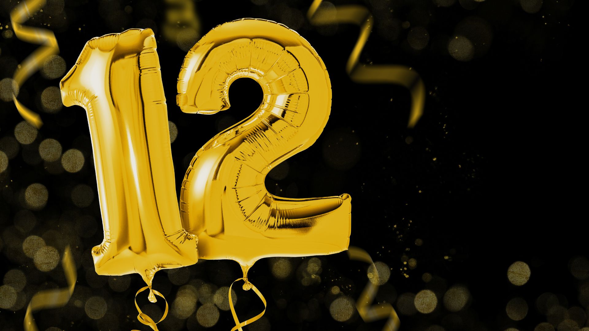 Imagem de um balões dourados com o número 12 e confetes dourados ao redor em um fundo preto