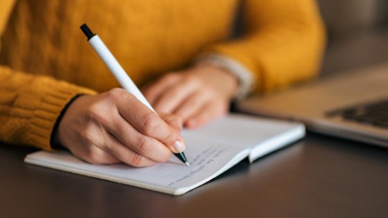 Mulher escrevendo em uma agenda com caneta