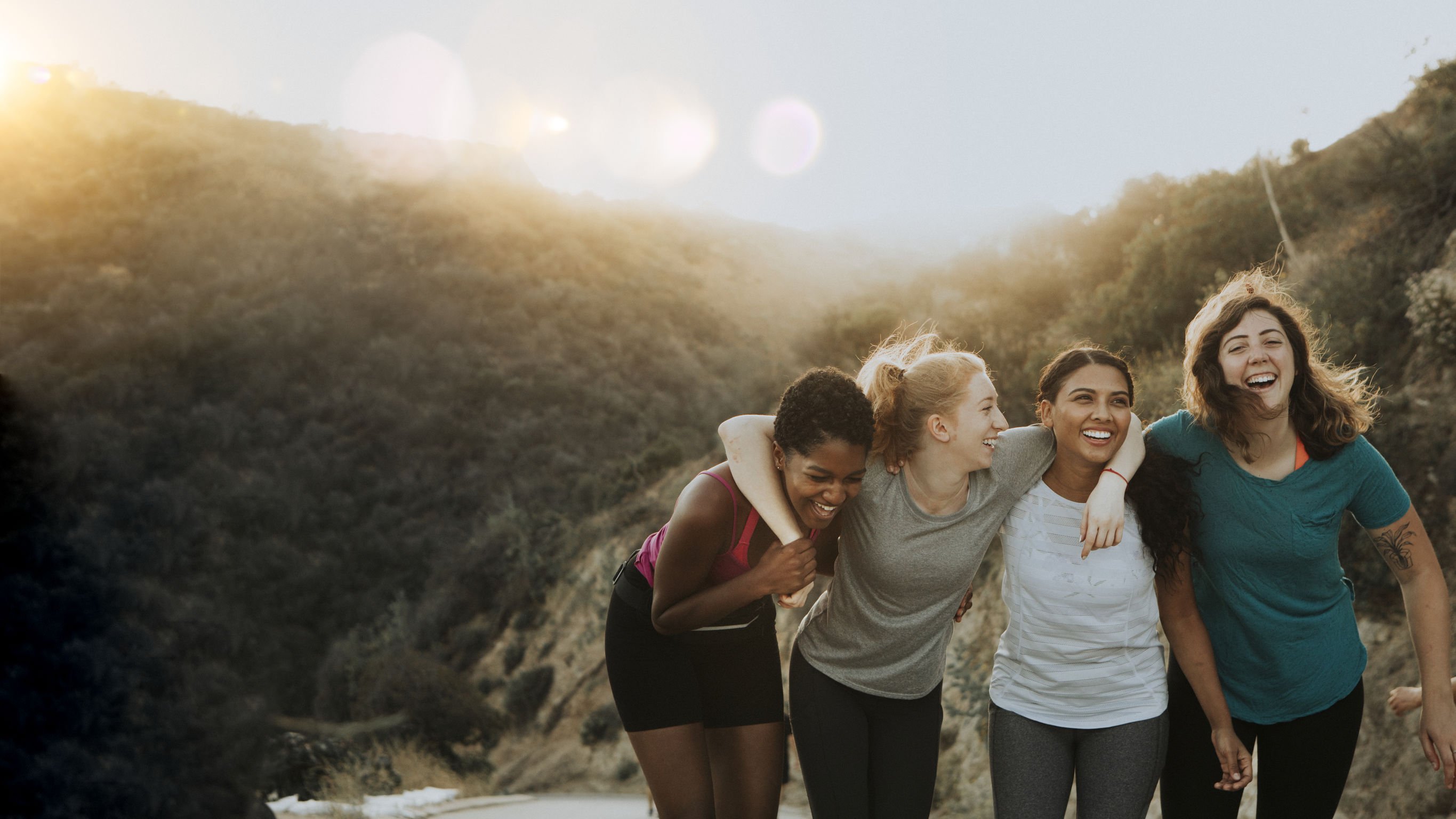 Quatro mulheres abraçadas sorrindo.