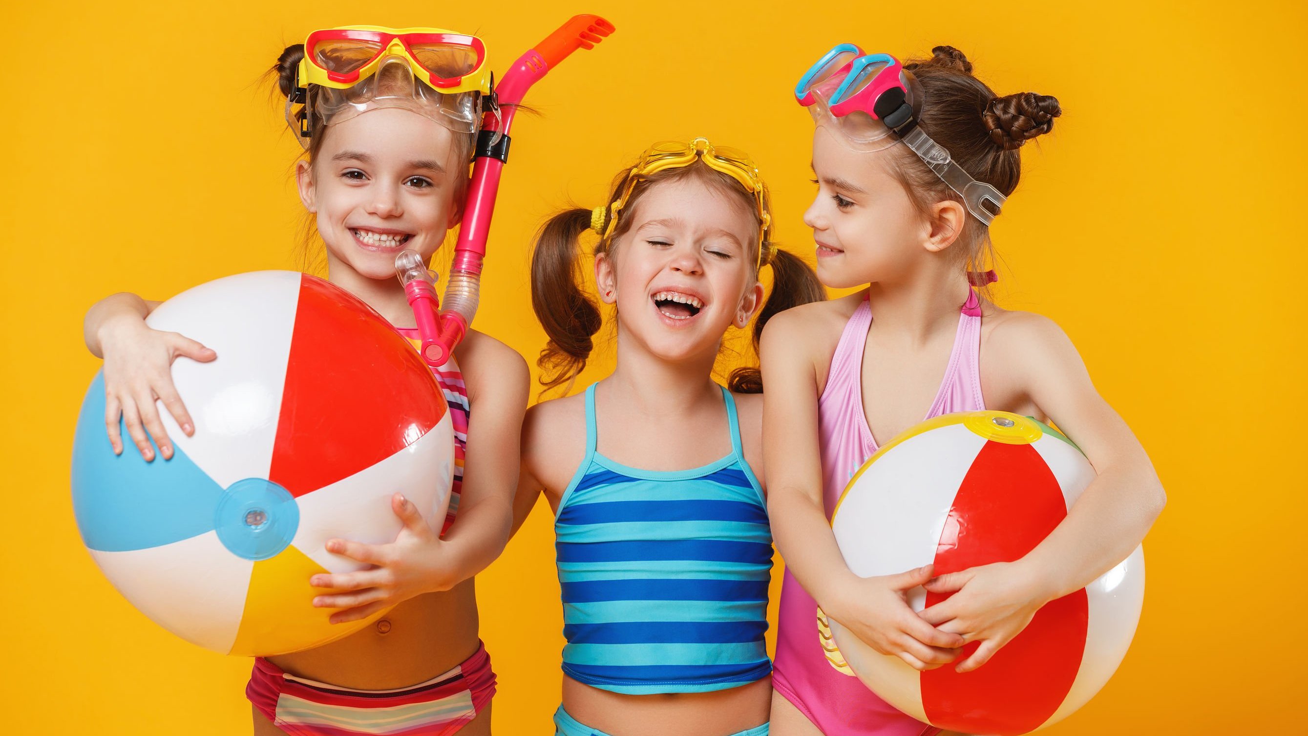 Meninas brancas com trajes de banho e expressões sorridentes