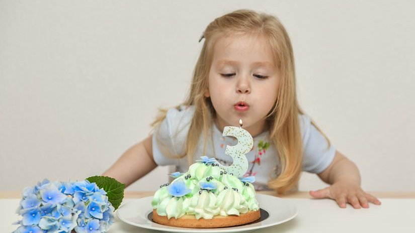 Criança soprando velas em cima de bolo