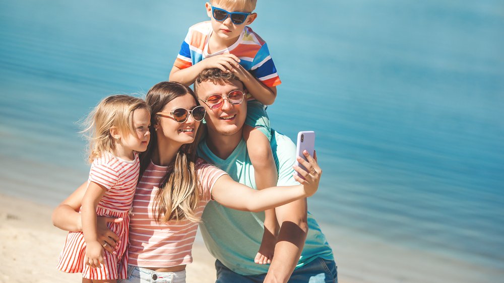 Família feliz tirando selfies na praia
