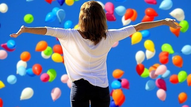 Balões coloridos voando e pessoa com braços abertos
