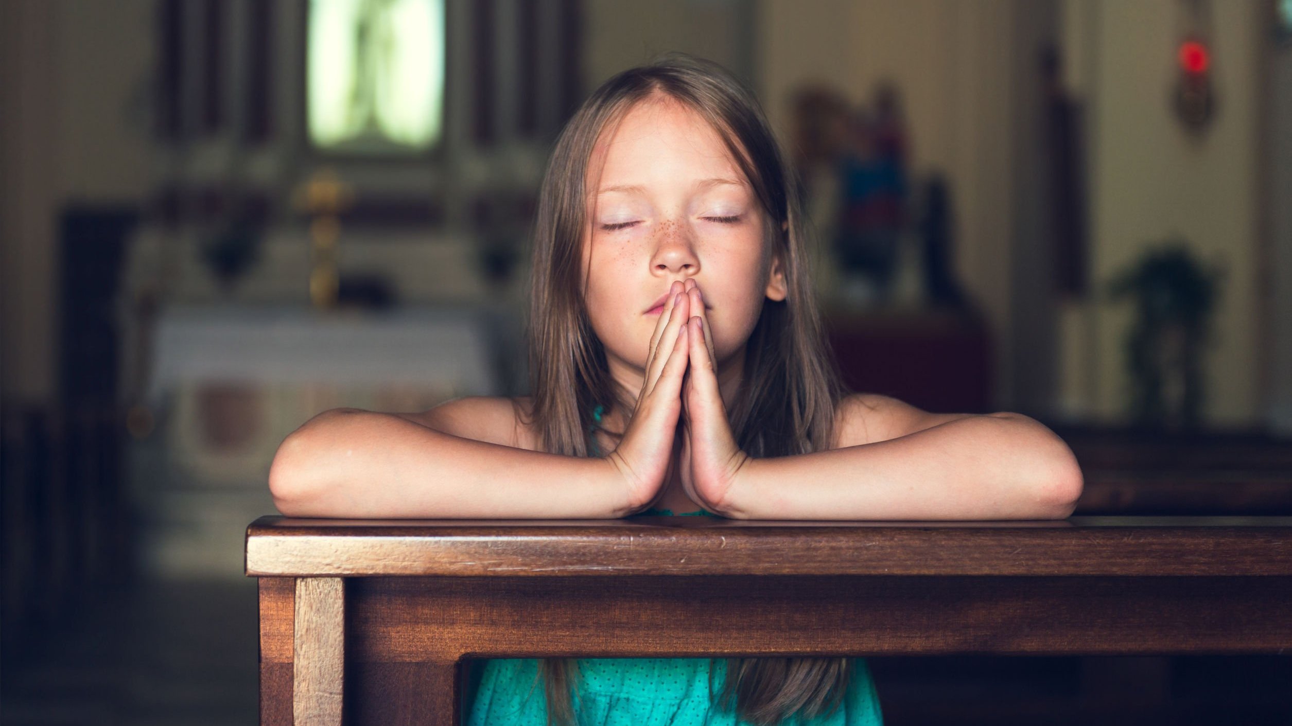 Garota com os olhos fechados enquanto reza